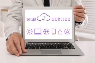 Image of Web hosting. Man showing laptop at table, closeup. Digital cloud with arrows, text and icons on screen