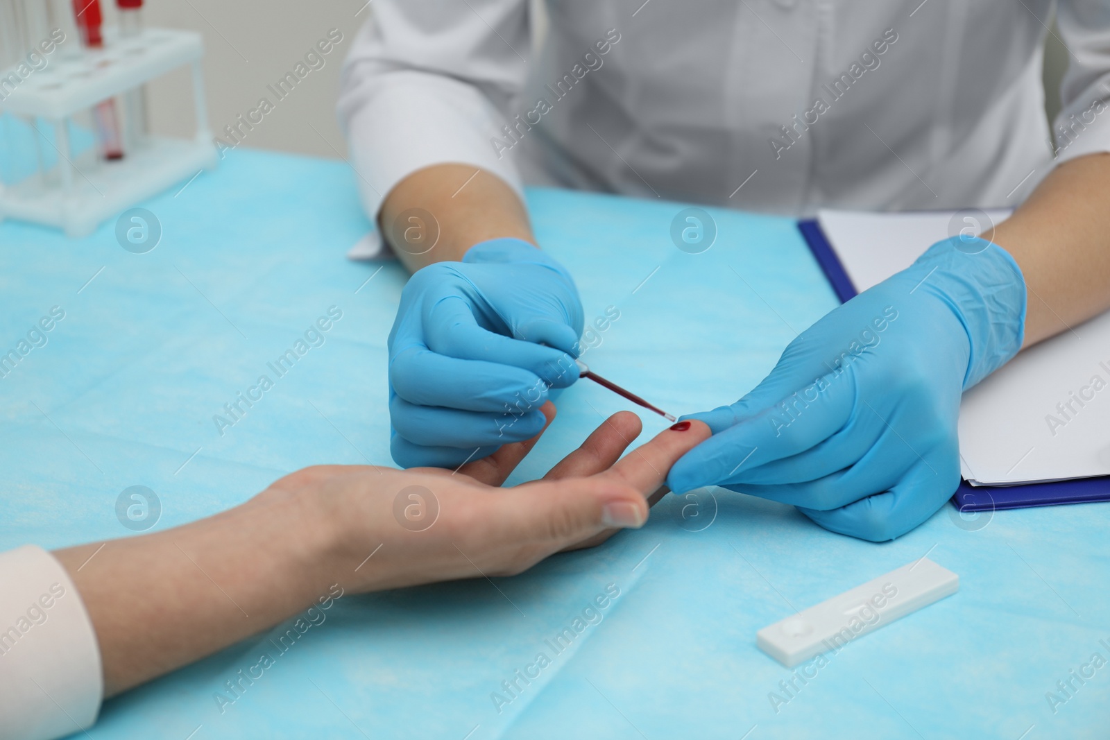 Photo of Doctor taking blood sample from patient's finger at table, closeup