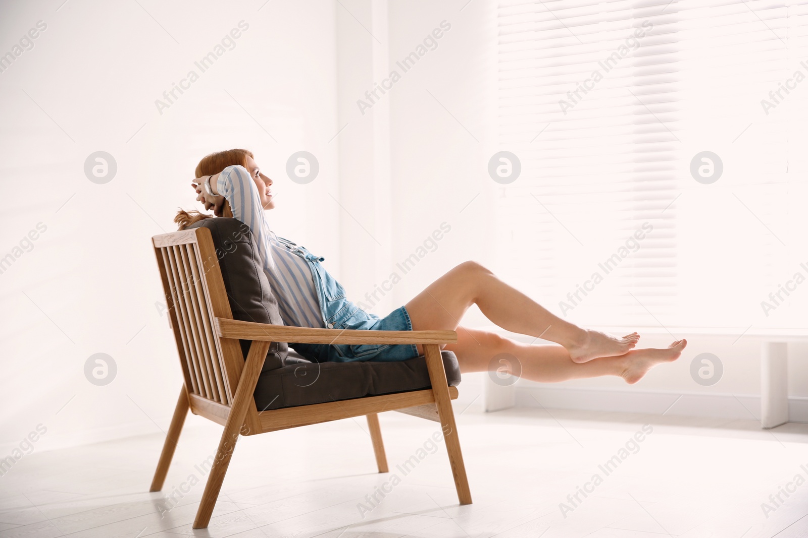 Photo of Young woman relaxing in armchair near window at home