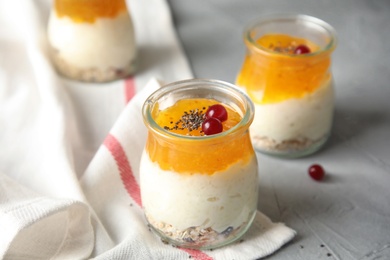 Photo of Creamy rice pudding with red currant, jam and oatmeal in jars on table