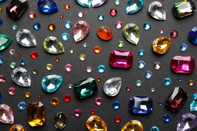 Different beautiful gemstones on black background, flat lay