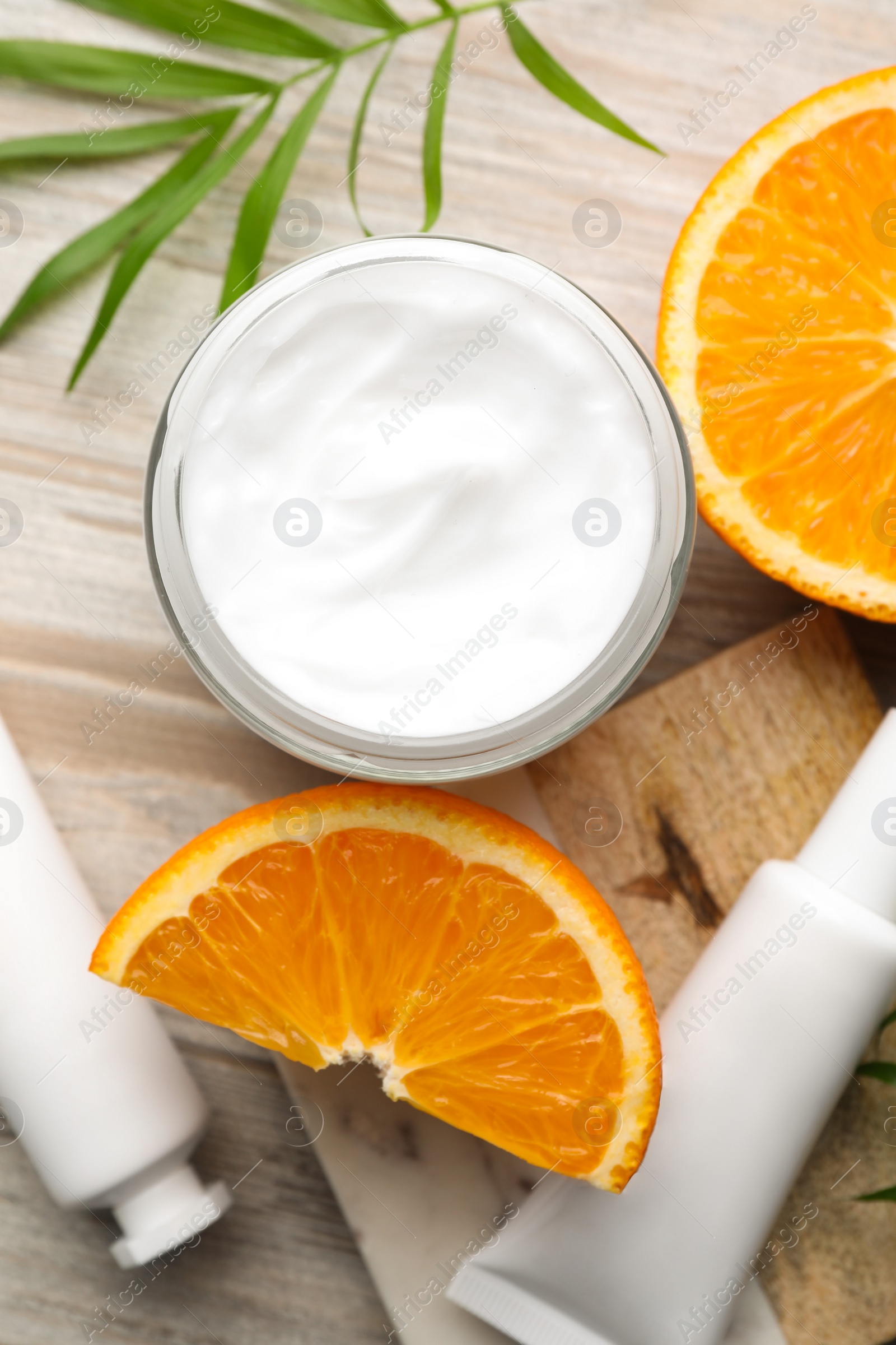 Photo of Different hand care cosmetic products, orange and green leaf on white wooden table, flat lay