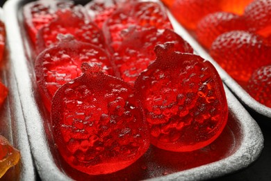 Photo of Delicious gummy pomegranate candies in container, closeup