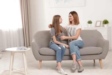 Happy mother talking with her teenager daughter at home