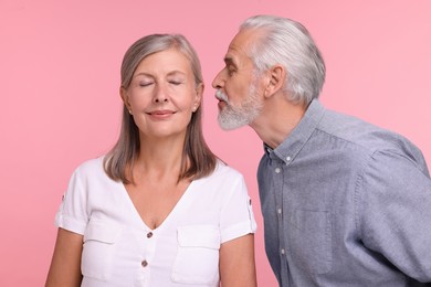 Photo of Senior man kissing his beloved woman on pink background