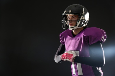 American football player wearing uniform on dark background. Space for text
