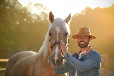 Photo of Man with adorable horse outdoors on sunny day. Lovely domesticated pet