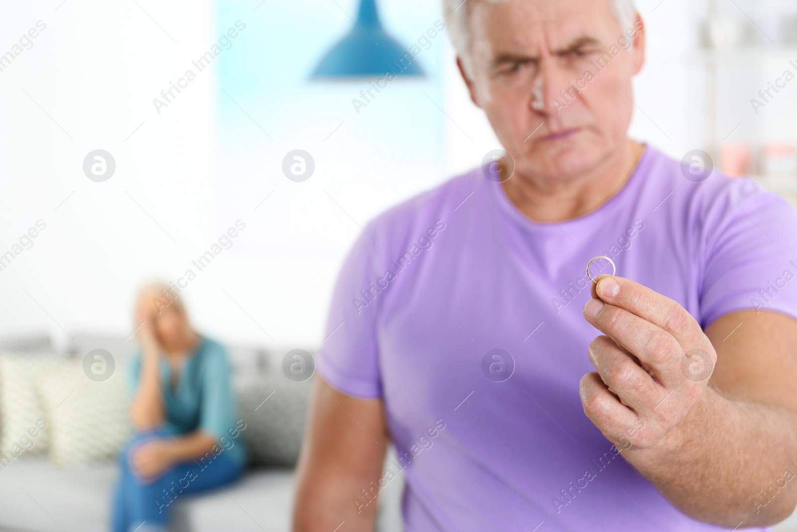 Photo of Mature man looking on wedding ring after conflict with his wife at home. Relationship problems