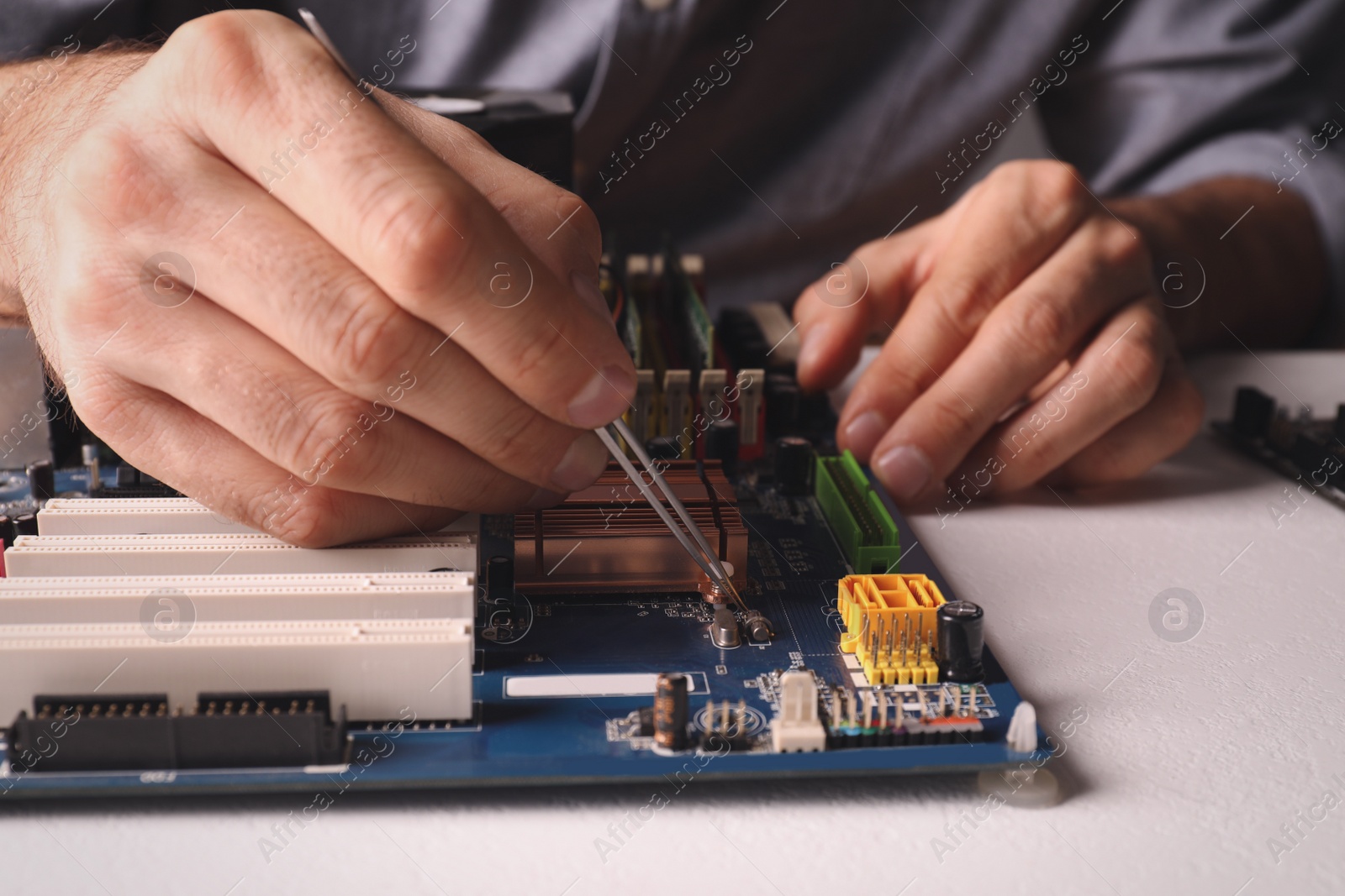 Photo of Technician repairing electronic circuit board at table, closeup