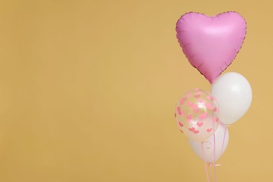 Bunch of heart and round shaped balloons on beige background, space for text. Birthday party