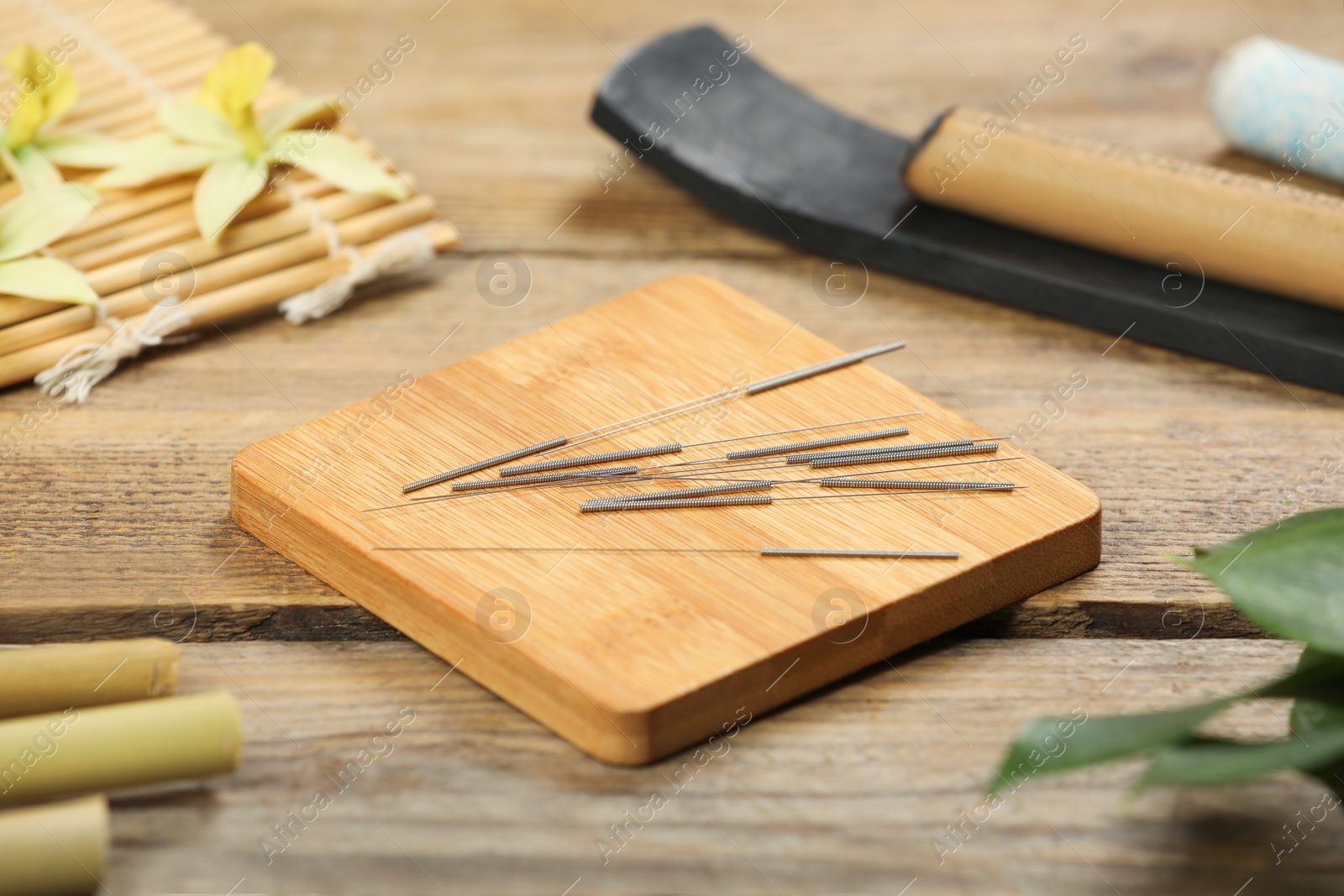 Photo of Board with acupuncture needles on wooden table