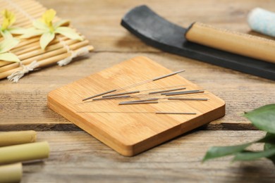 Photo of Board with acupuncture needles on wooden table