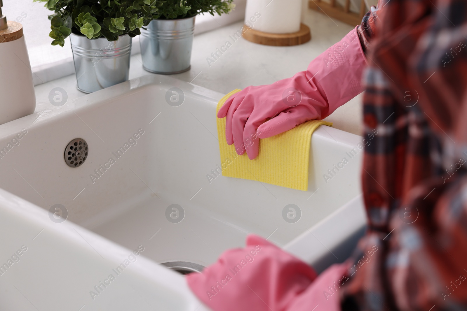 Photo of Woman cleaning kitchen sink with microfiber cloth at home, closeup