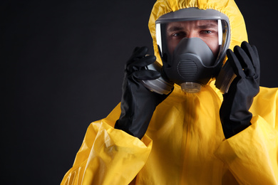 Photo of Man wearing chemical protective suit on black background, closeup. Virus research