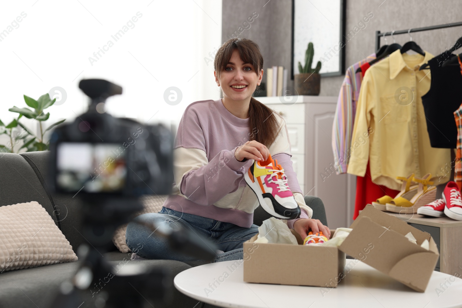 Photo of Smiling fashion blogger showing her shoes while recording video at home