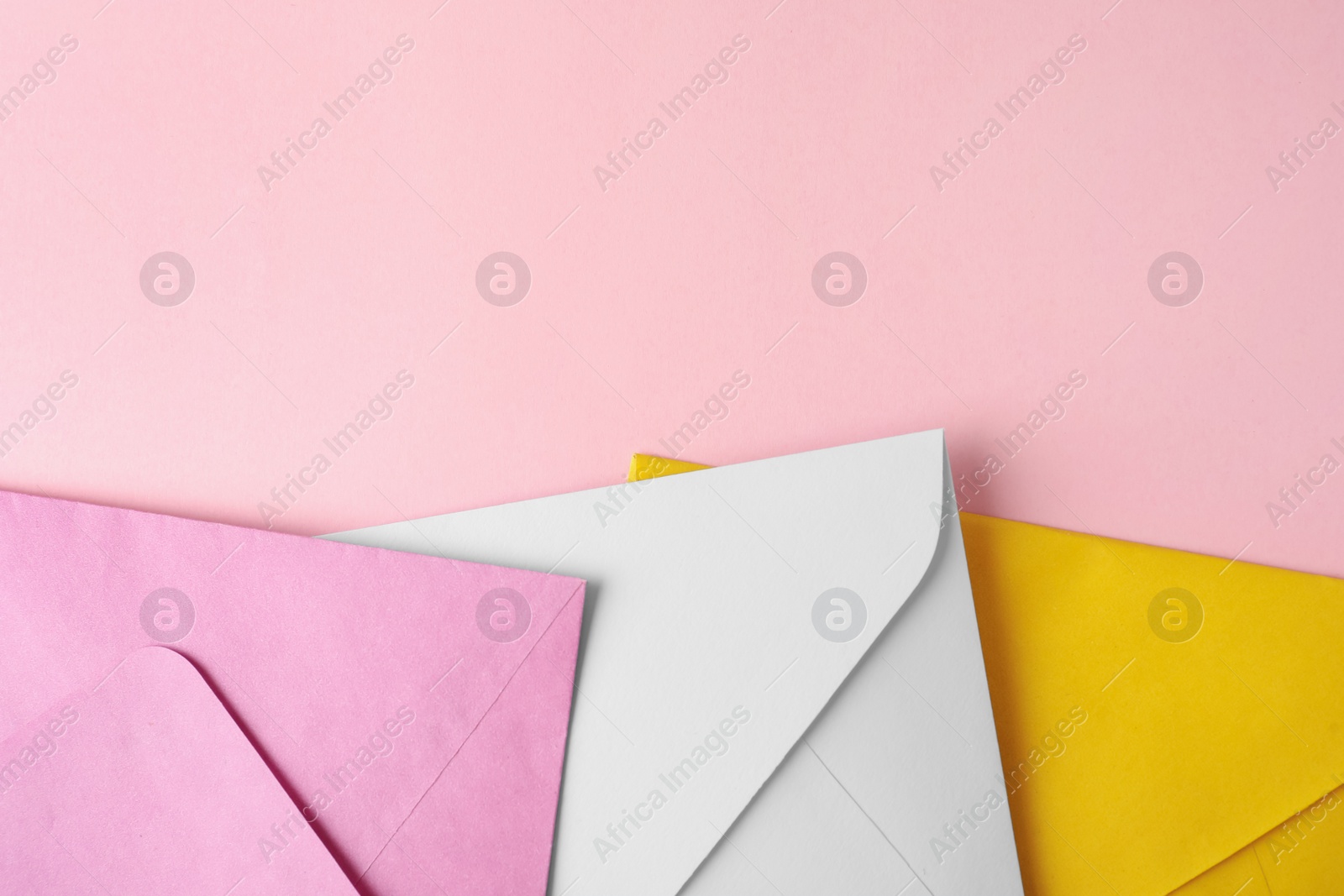 Photo of Colorful paper envelopes on pink background, flat lay. Space for text