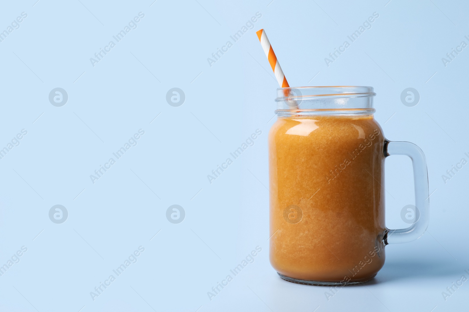 Photo of Mason jar with delicious fruit smoothie on light blue background. Space for text