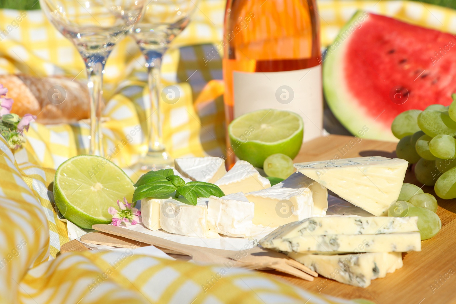 Photo of Delicious cheeses with basil and fruits on picnic blanket, closeup