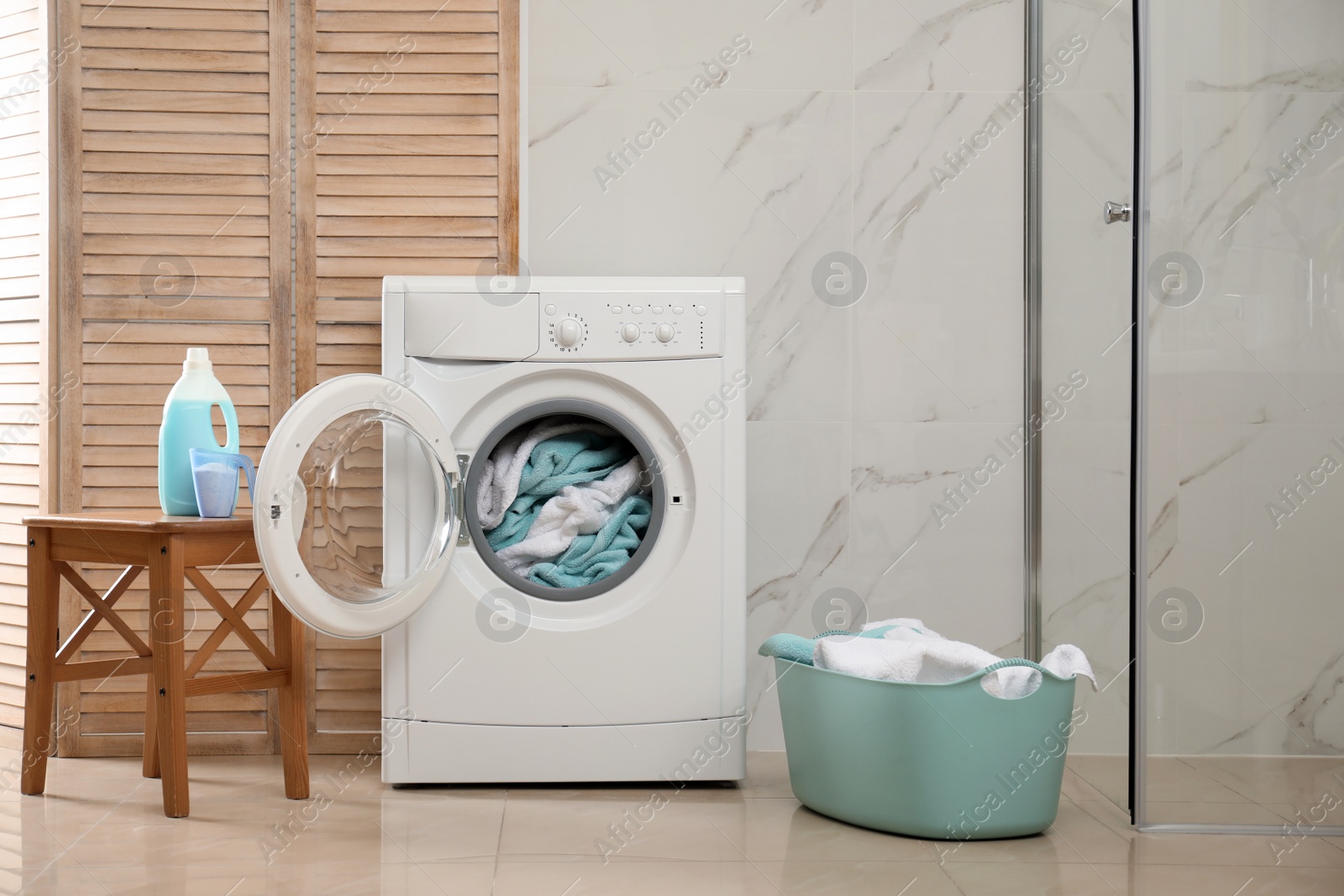 Photo of Modern washing machine with towels in bathroom