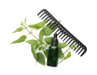Photo of Stinging nettle extract in bottle, green leaves and comb on white background, top view. Natural hair care