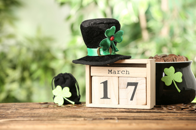 Photo of Composition with block calendar on wooden table against blurred greenery. St. Patrick's Day celebration
