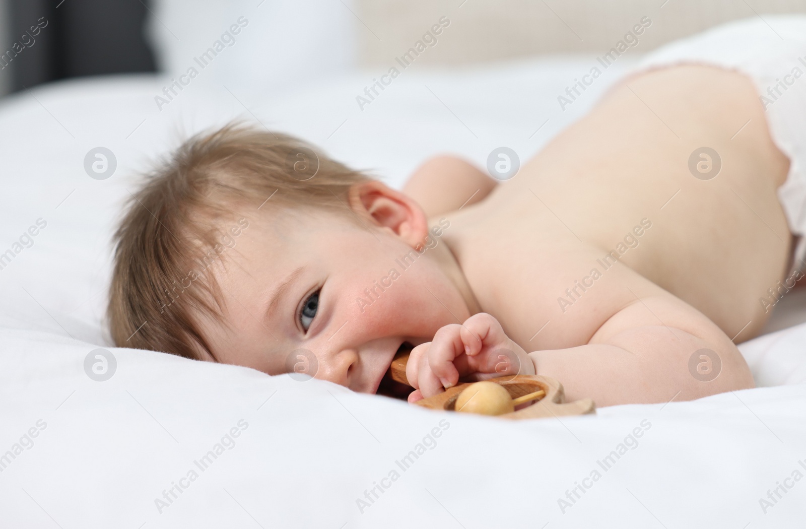 Photo of Cute baby boy with rattle on bed at home