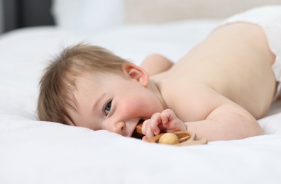 Photo of Cute baby boy with rattle on bed at home