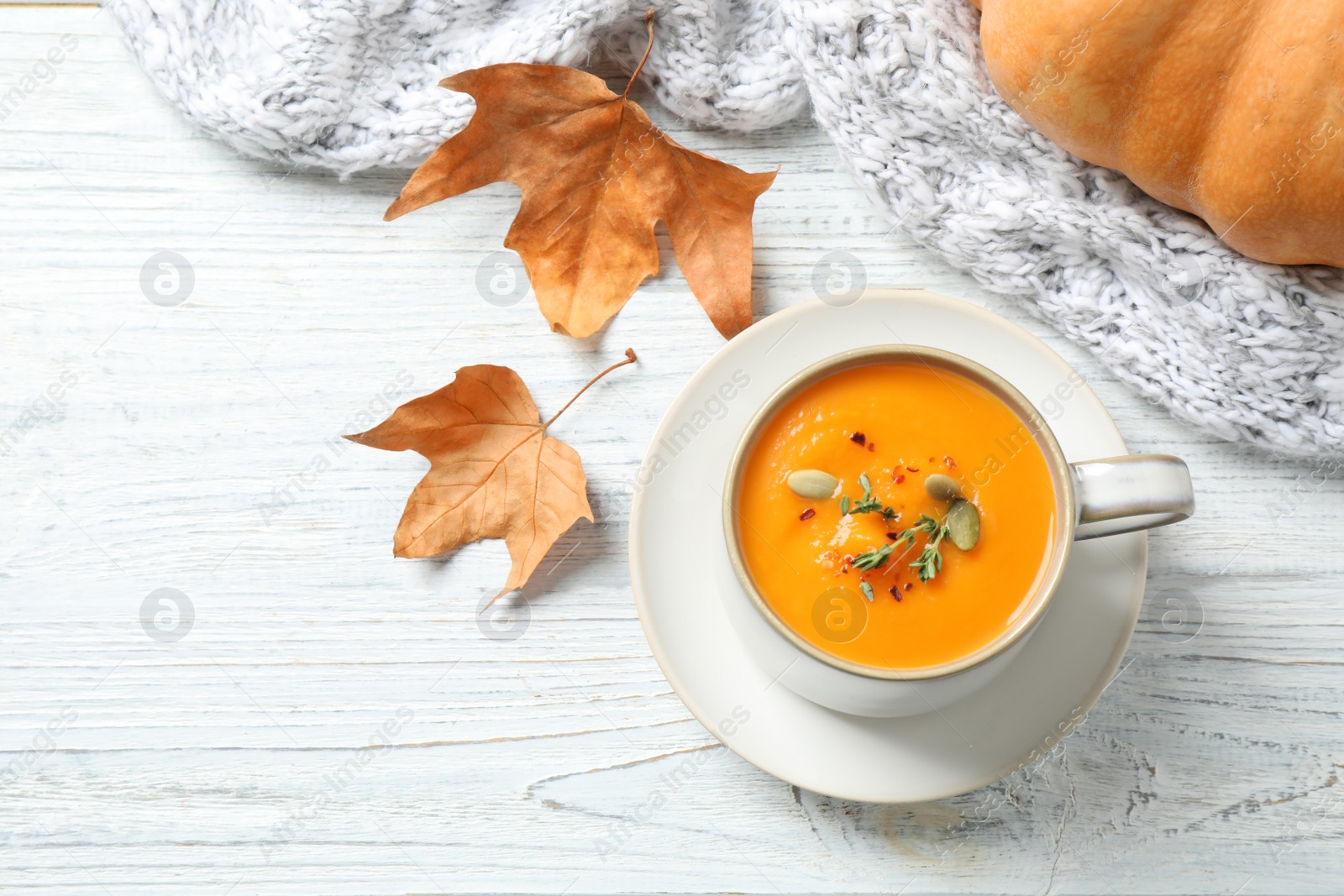 Photo of Delicious pumpkin soup in cup on white wooden table, flat lay