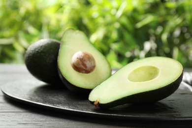 Photo of Delicious ripe avocados on table against blurred background