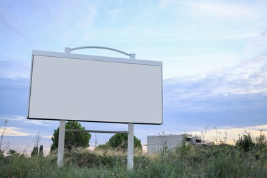 Photo of One blank billboard under blue sky in meadow. Mockup for design