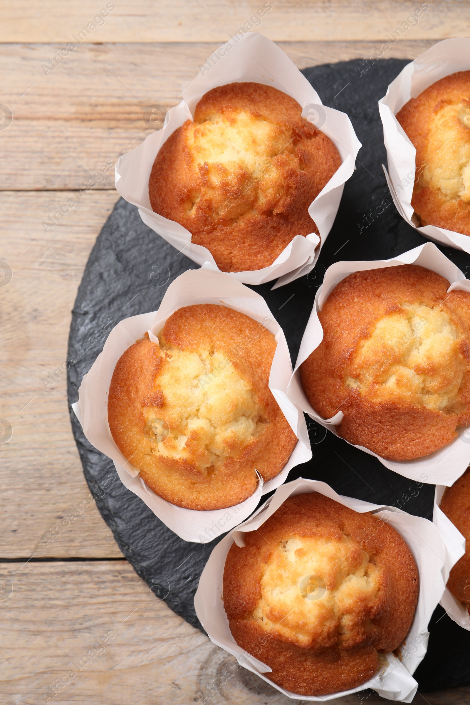 Photo of Delicious sweet muffins on wooden table, top view