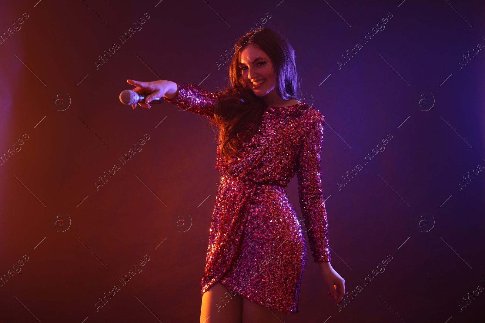 Photo of Emotional singer giving microphone to others in color lights