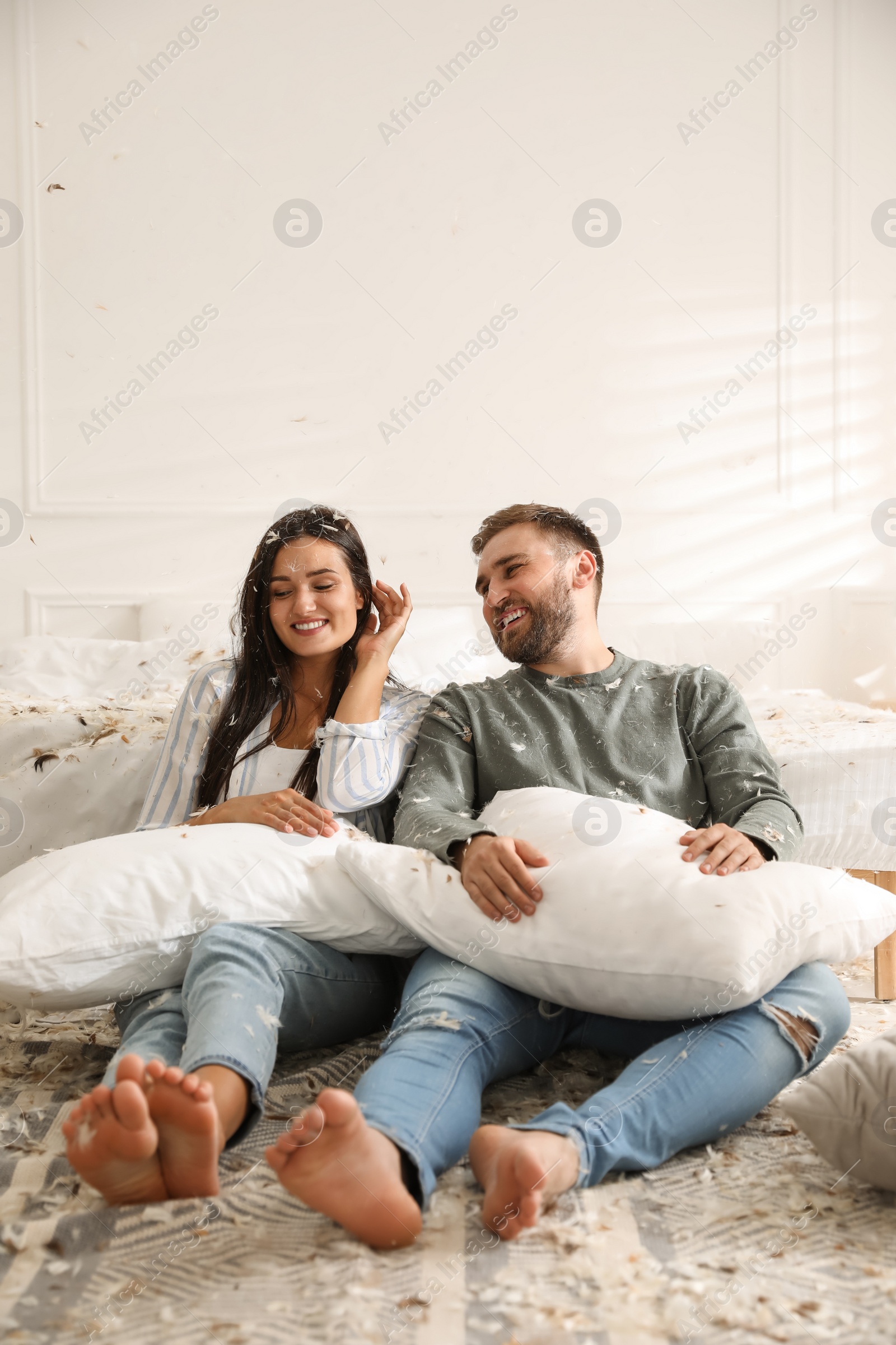 Photo of Happy young couple resting after fun pillow fight in bedroom