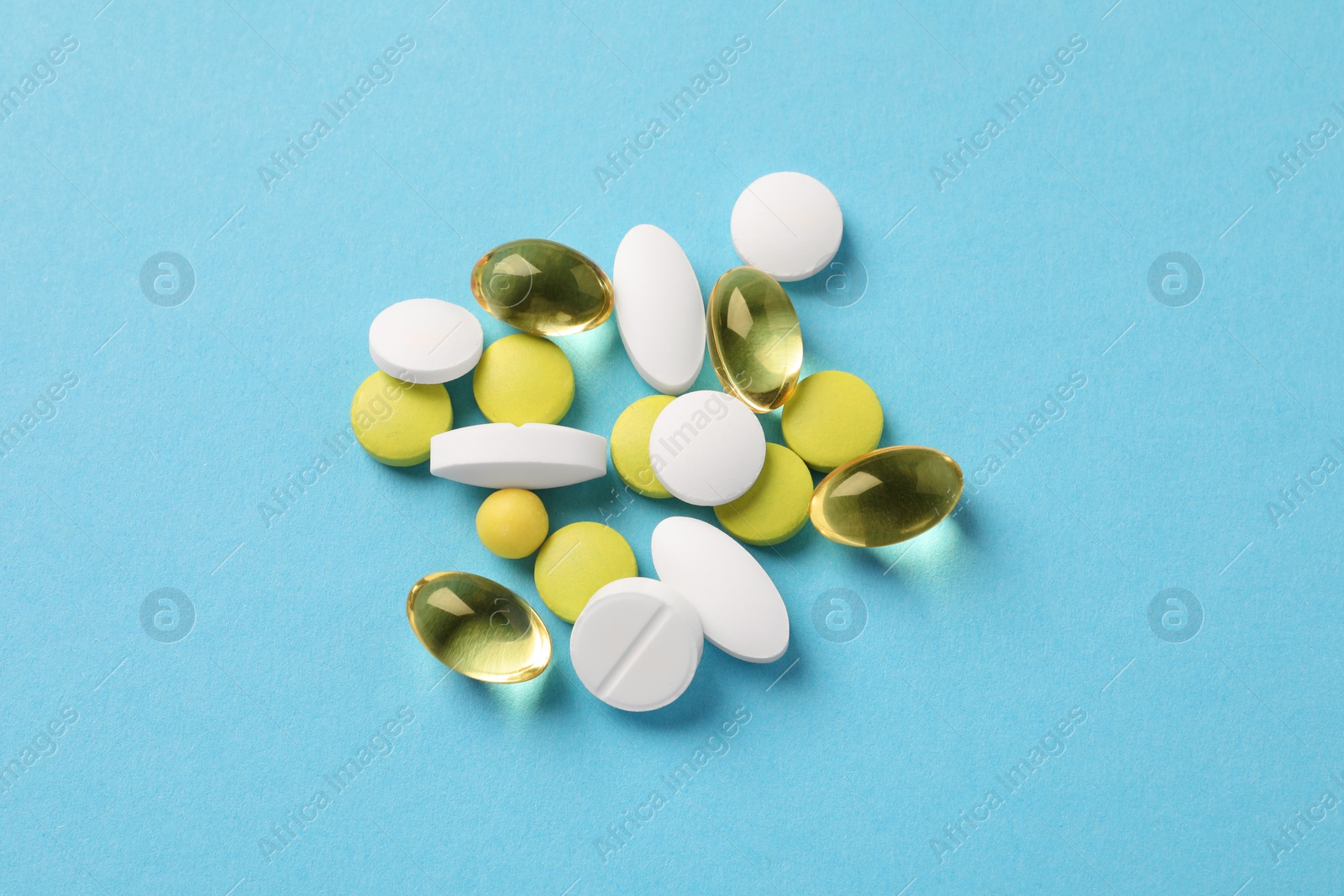 Photo of Pile of different pills on light blue background, flat lay