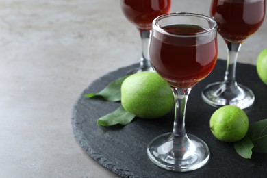 Photo of Delicious liqueur and green walnuts on grey table, closeup. Space for text