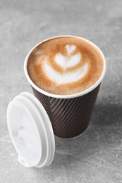 Coffee to go. Paper cup with tasty drink on grey table, closeup