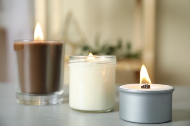 Burning candles in holders on light grey table