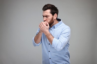 Photo of Sick man coughing on light grey background. Cold symptoms