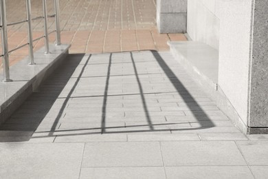 Photo of Tiled ramp with metal handrail near building outdoors