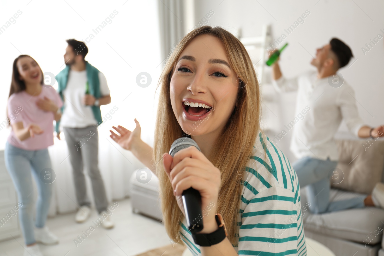 Photo of Young woman singing karaoke with friends at home