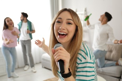 Young woman singing karaoke with friends at home