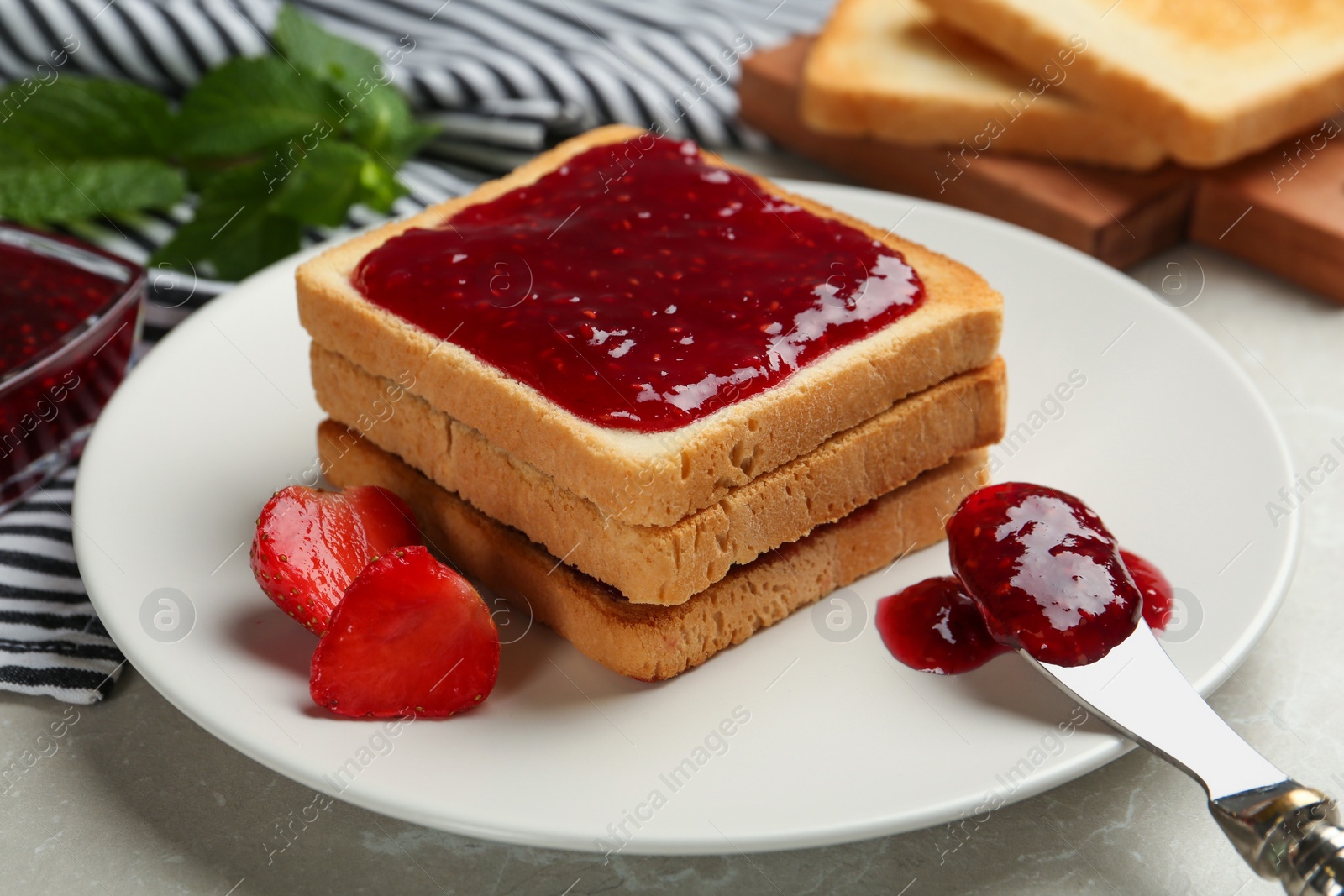 Photo of Toasts served with tasty jam and strawberry on light table, closeup