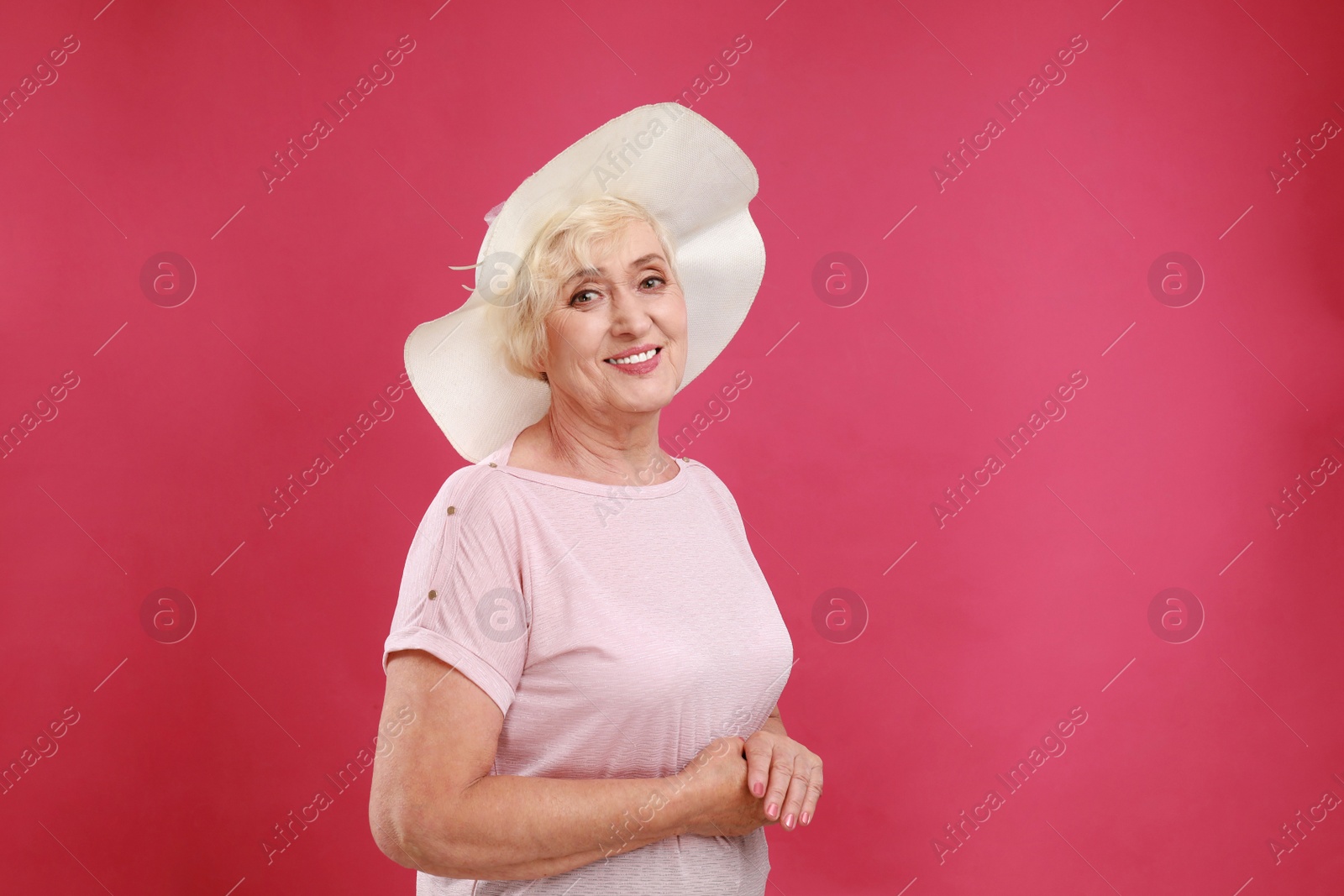 Photo of Senior woman with hat on crimson background