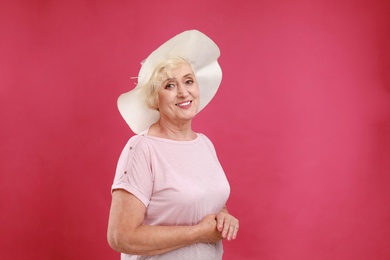 Senior woman with hat on crimson background