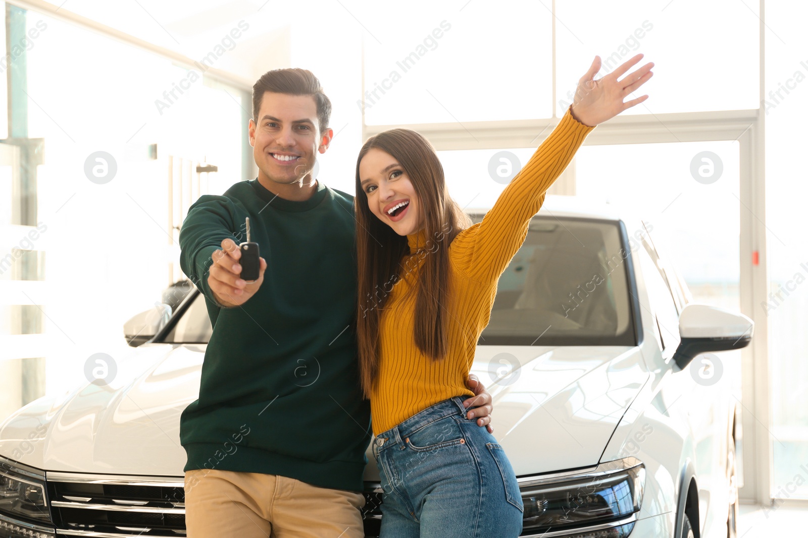 Photo of Happy couple with car key in modern auto dealership