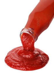 Photo of Pouring tasty ketchup from bottle isolated on white. Tomato sauce