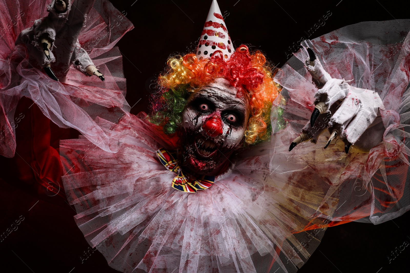 Photo of Terrifying clown on dark background. Halloween party costume