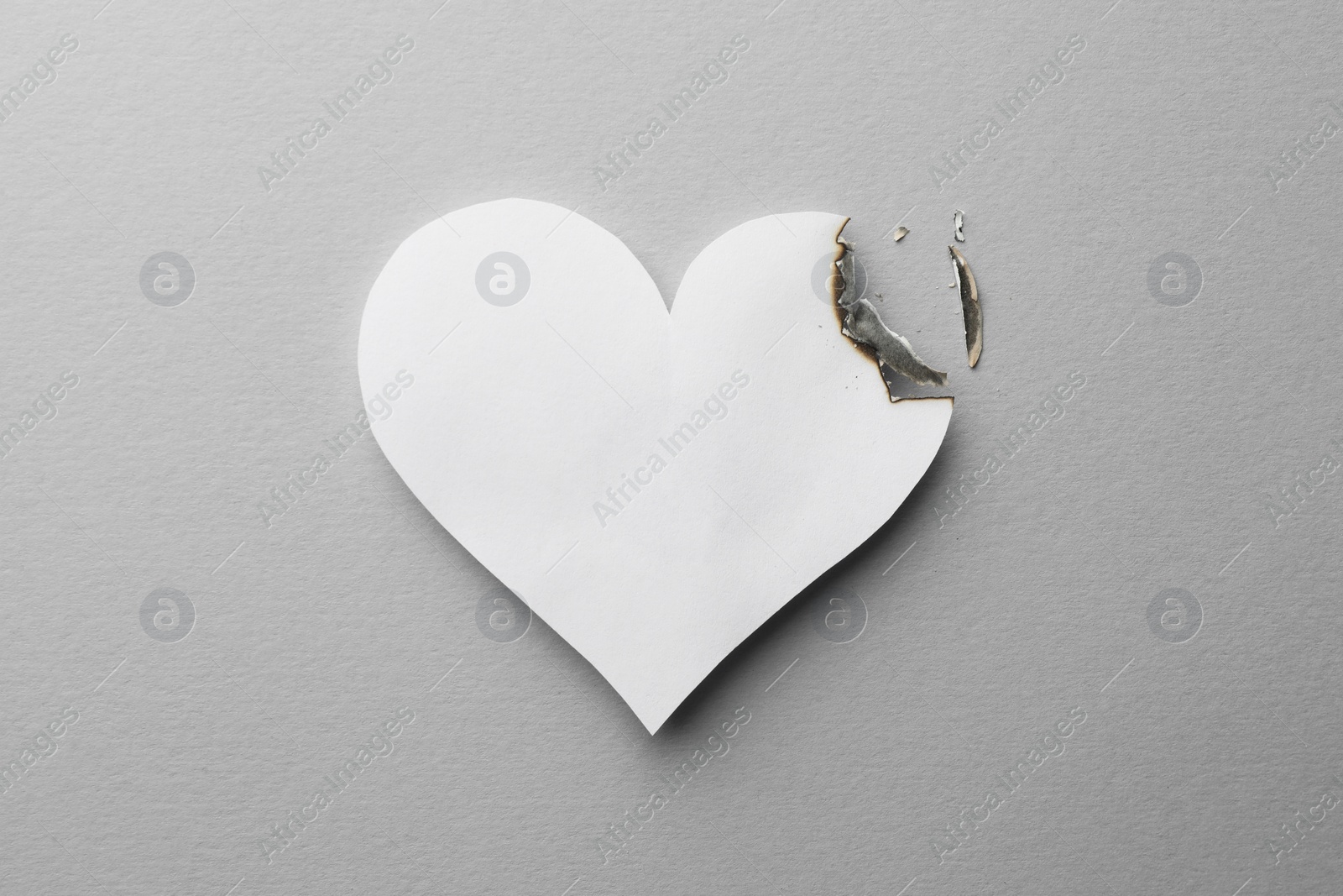 Photo of Burned paper heart on white background, top view. Broken heart