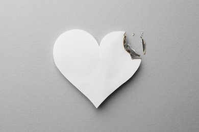 Burned paper heart on white background, top view. Broken heart