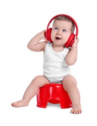 Photo of Little child with headphones sitting on baby potty against white background
